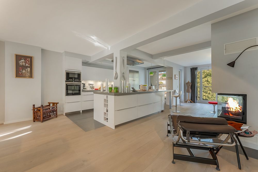 Moderne offene Küche mit Kochinsel, Essbereich und Kamin neben einem Sessel.
