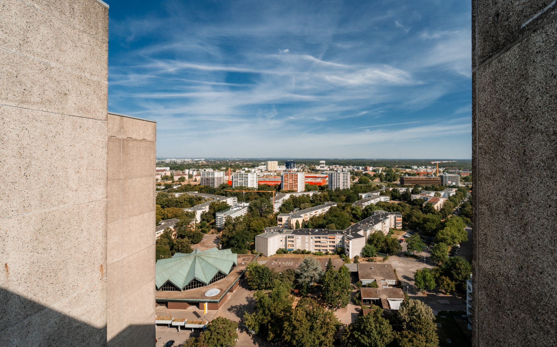 Blick von oben auf Wohngebäude, Bäume und Straßen zwischen zwei Betonwänden.