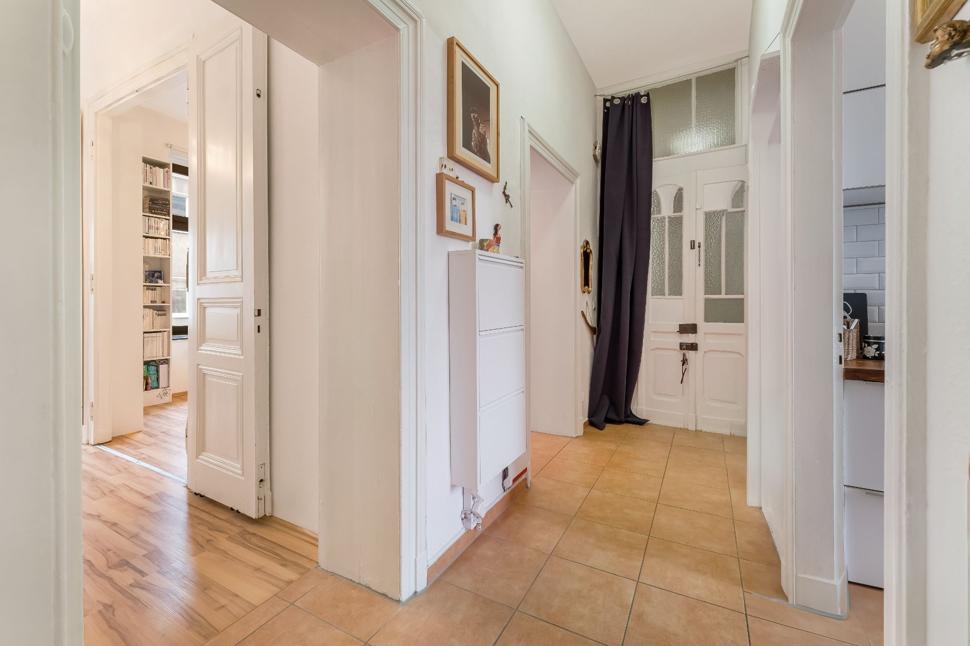 Heller Flur in einer Wohnung mit Fliesenboden und mehreren offenen Türen.