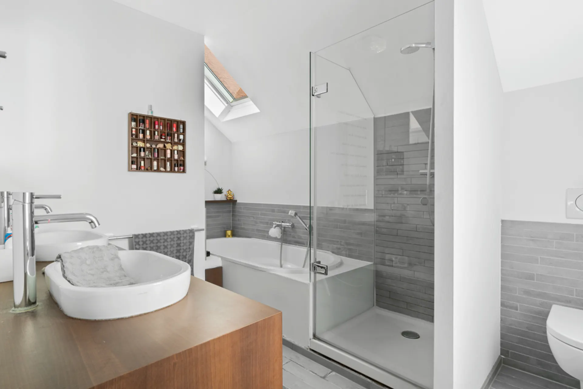 Modernes Badezimmer mit Glasdusche, Badewanne, Waschbecken und Dachfenster.