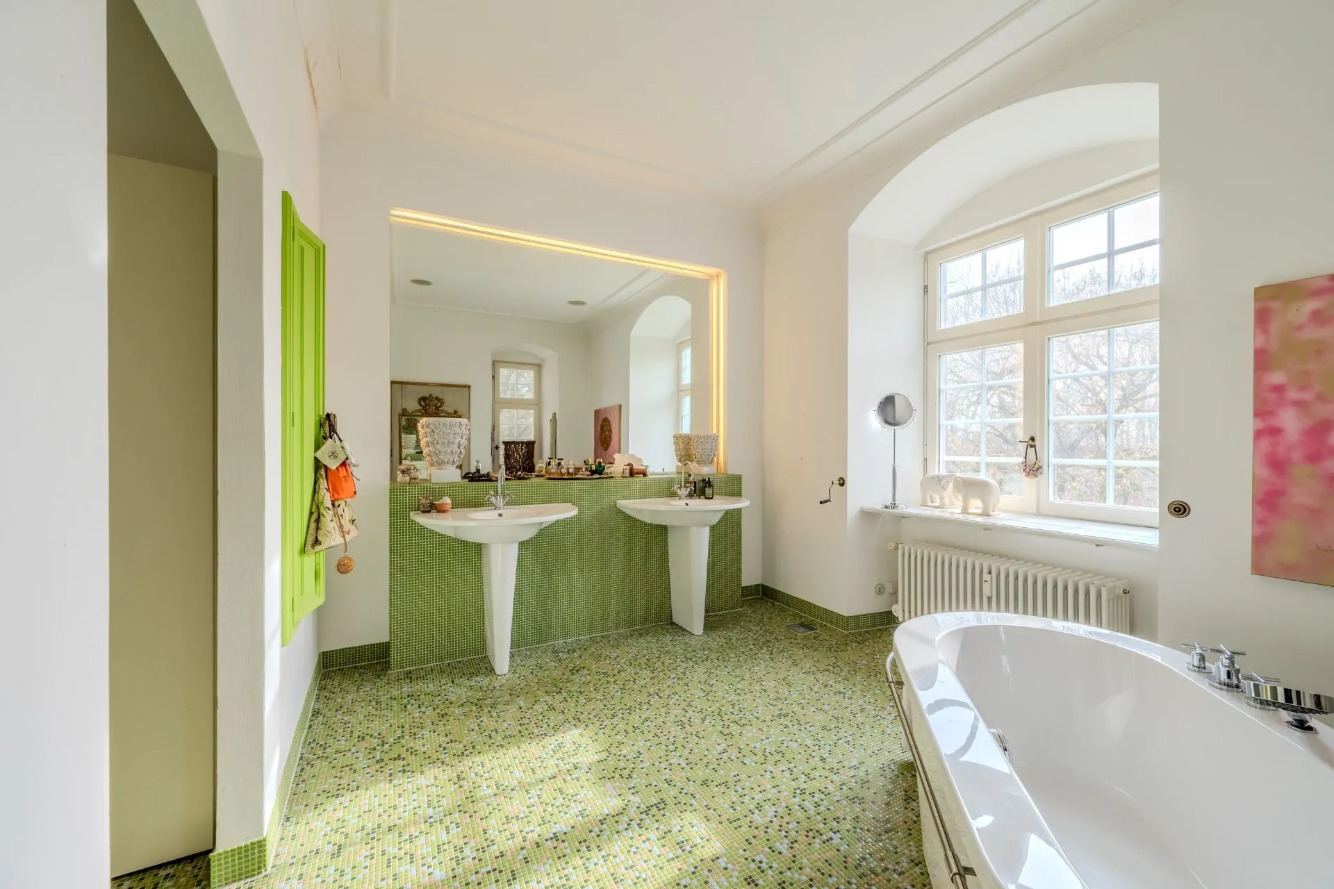 Helles Badezimmer mit zwei Waschbecken, großer Badewanne und Fenster mit Tageslicht.
