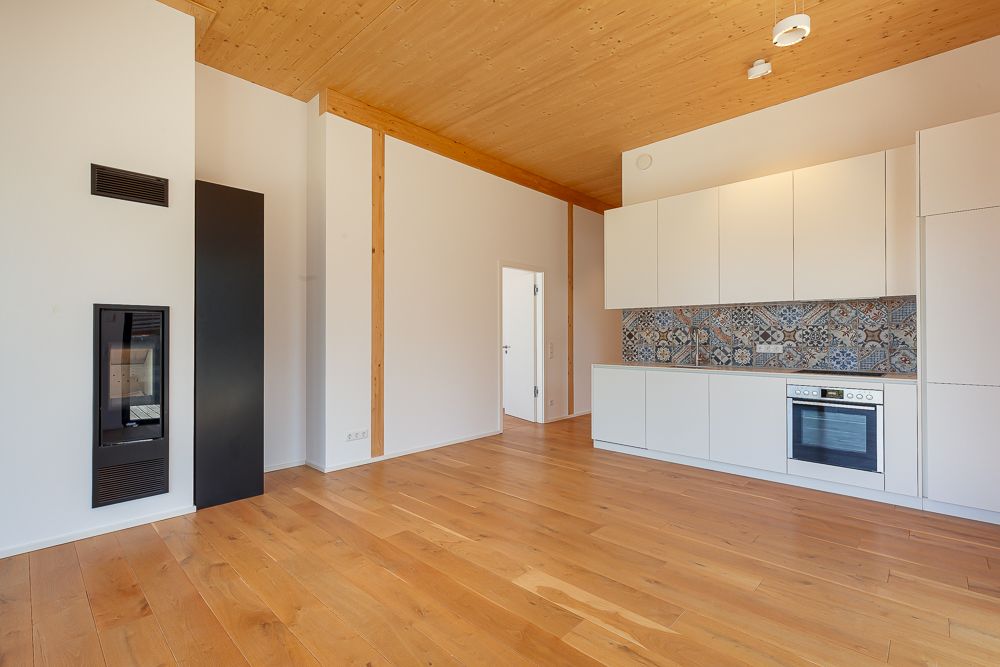 Helle Wohnküche mit Holzboden, Kamin und moderner Einbauküche mit gemustertem Fliesenspiegel.
