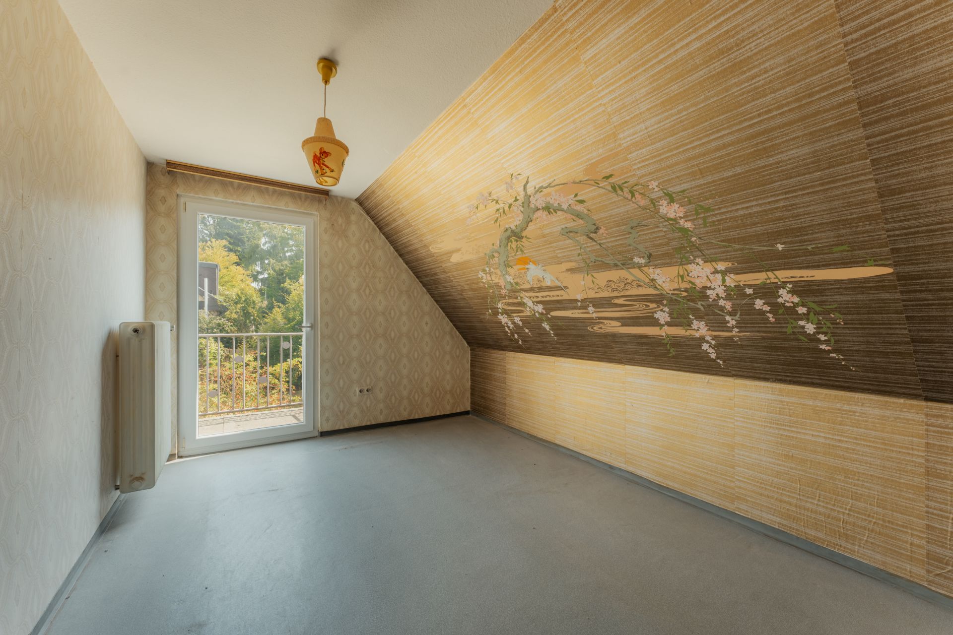 Leeres Zimmer mit schräger Wand, gemalter Blütenranke und Tür zum Balkon.