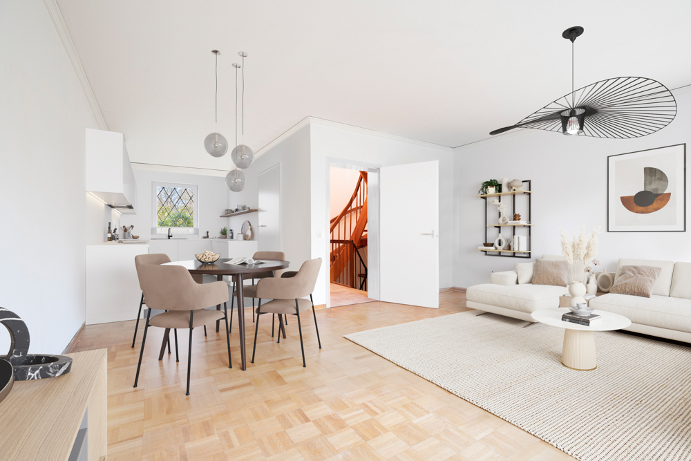 Helles Wohnzimmer mit Sofa, Esstisch, offener Küche und Treppe im Hintergrund.