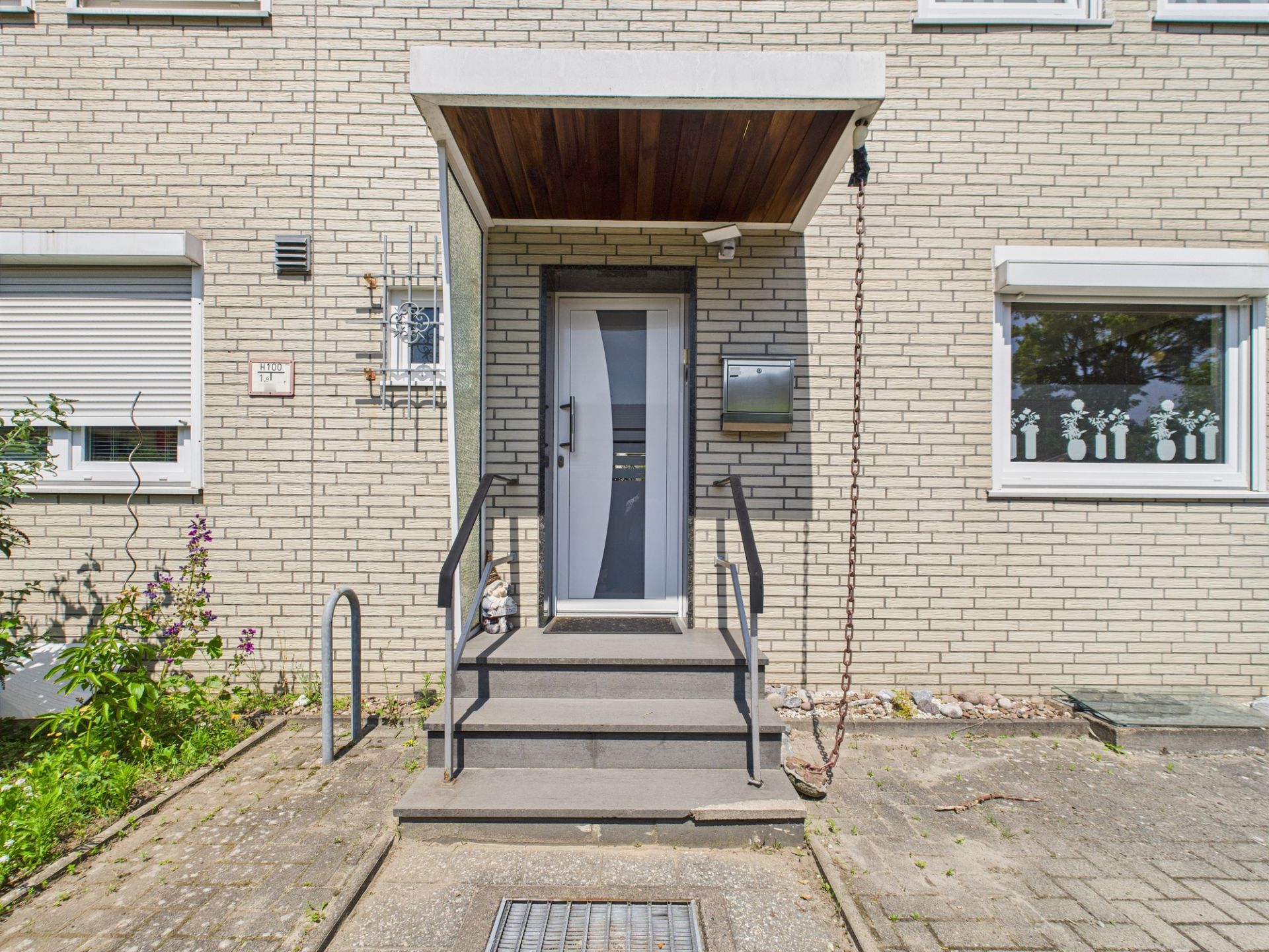 Eingangstür eines Wohnhauses mit Treppe, Geländer und Briefkasten.