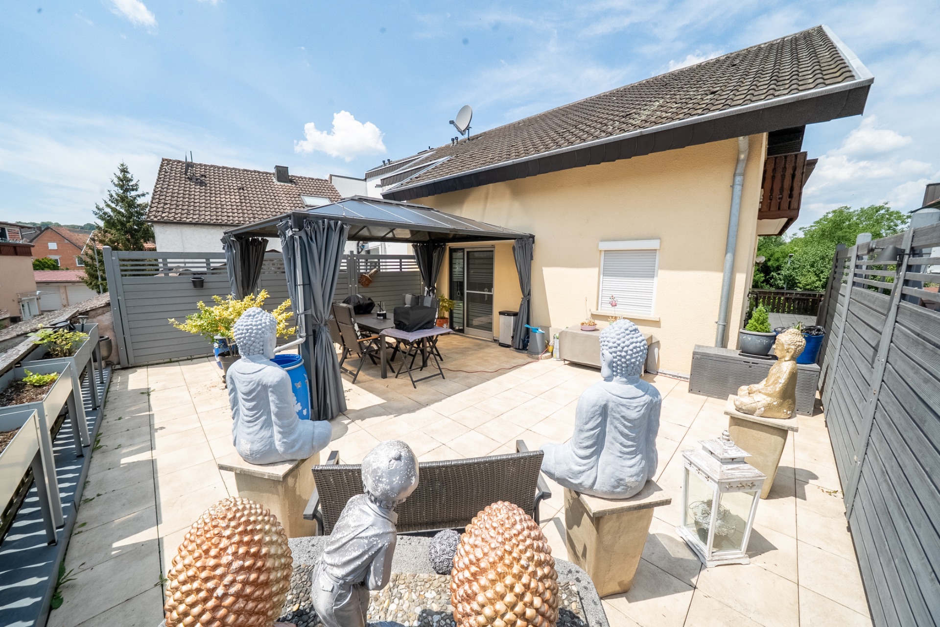 Große Terrasse mit Sitzbereich, Pavillon und mehreren Buddha-Statuen.