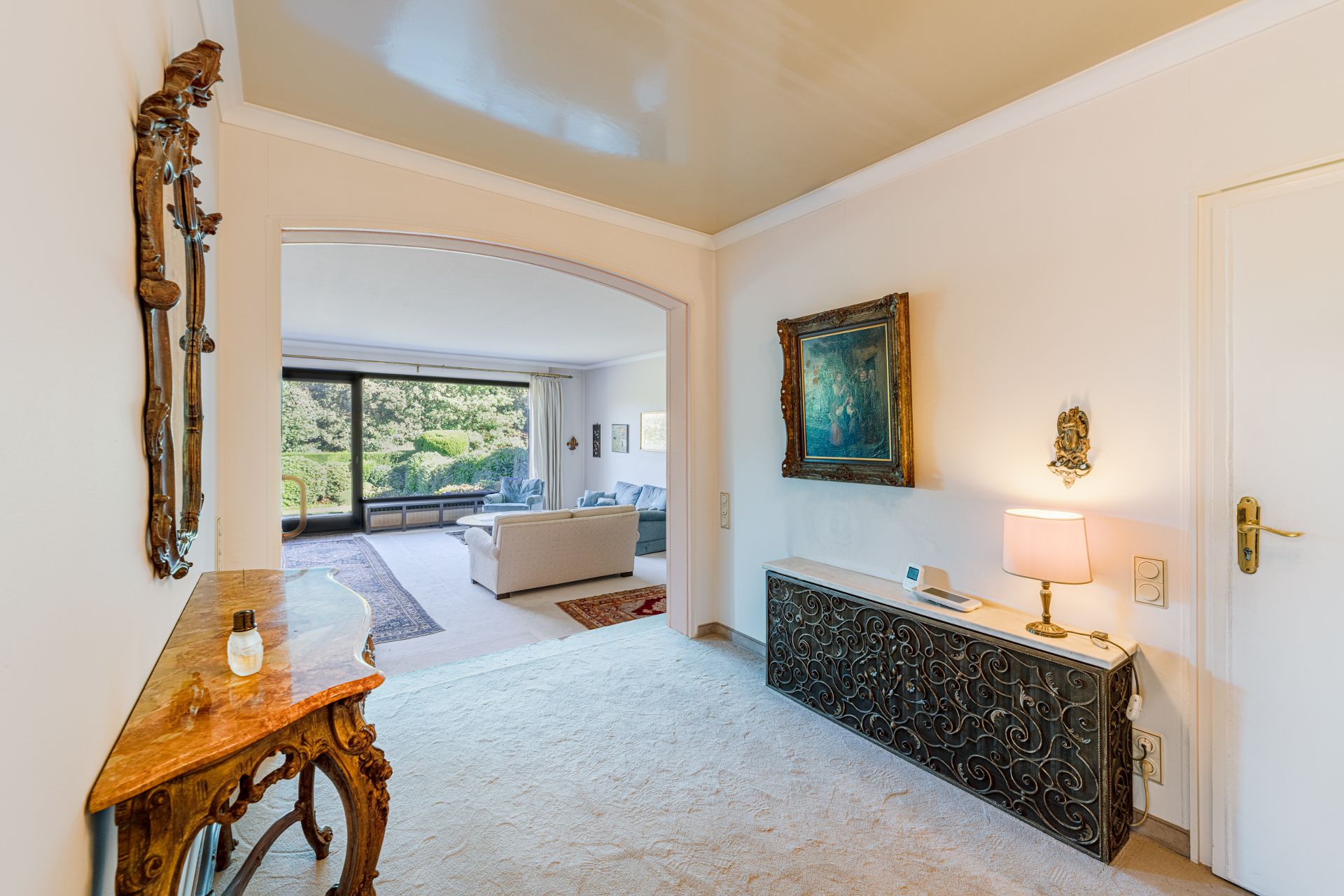 Heller Flur mit Spiegel, Kommode und Blick in ein Wohnzimmer mit großen Fenstern.