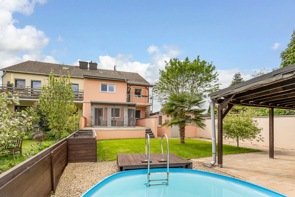 Garten mit Pool, Terrasse, Bäumen und überdachtem Sitzbereich vor einem Wohnhaus.