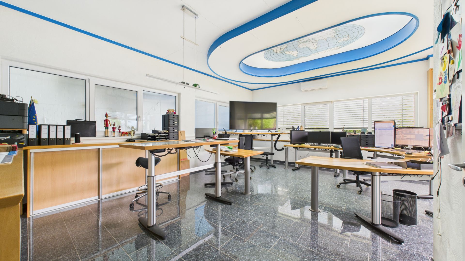 Modernes Home-Office mit mehreren Schreibtischen, Computern und großen Fenstern.