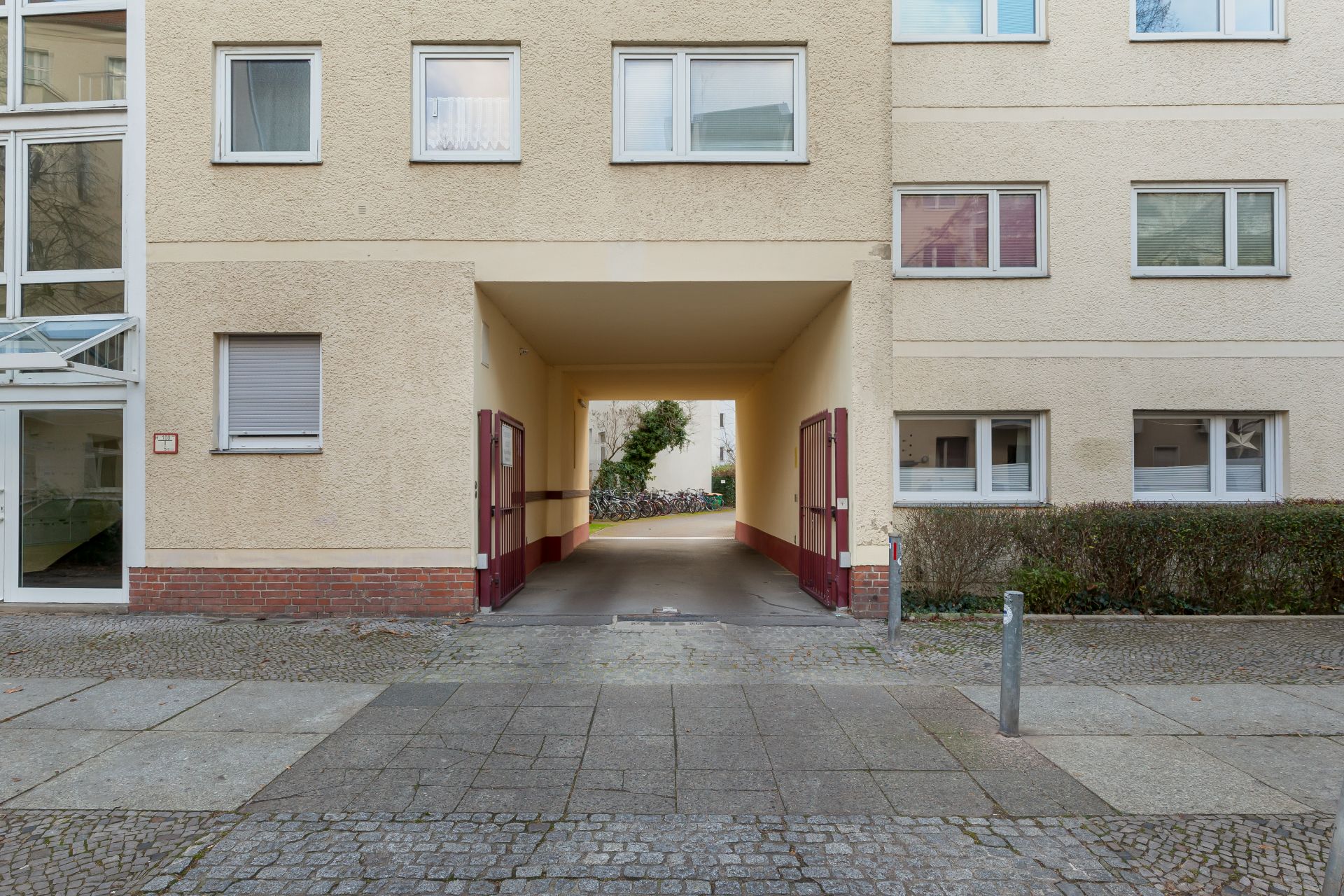 Durchgang durch ein Wohnhaus mit offenen Hoftoren und Blick auf Fahrräder im Hinterhof.