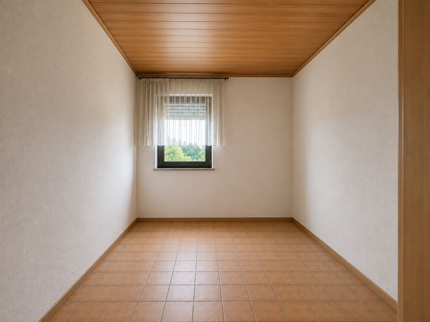 Leerer Raum mit Fliesenboden, Holzdecke und einem Fenster mit Vorhängen.