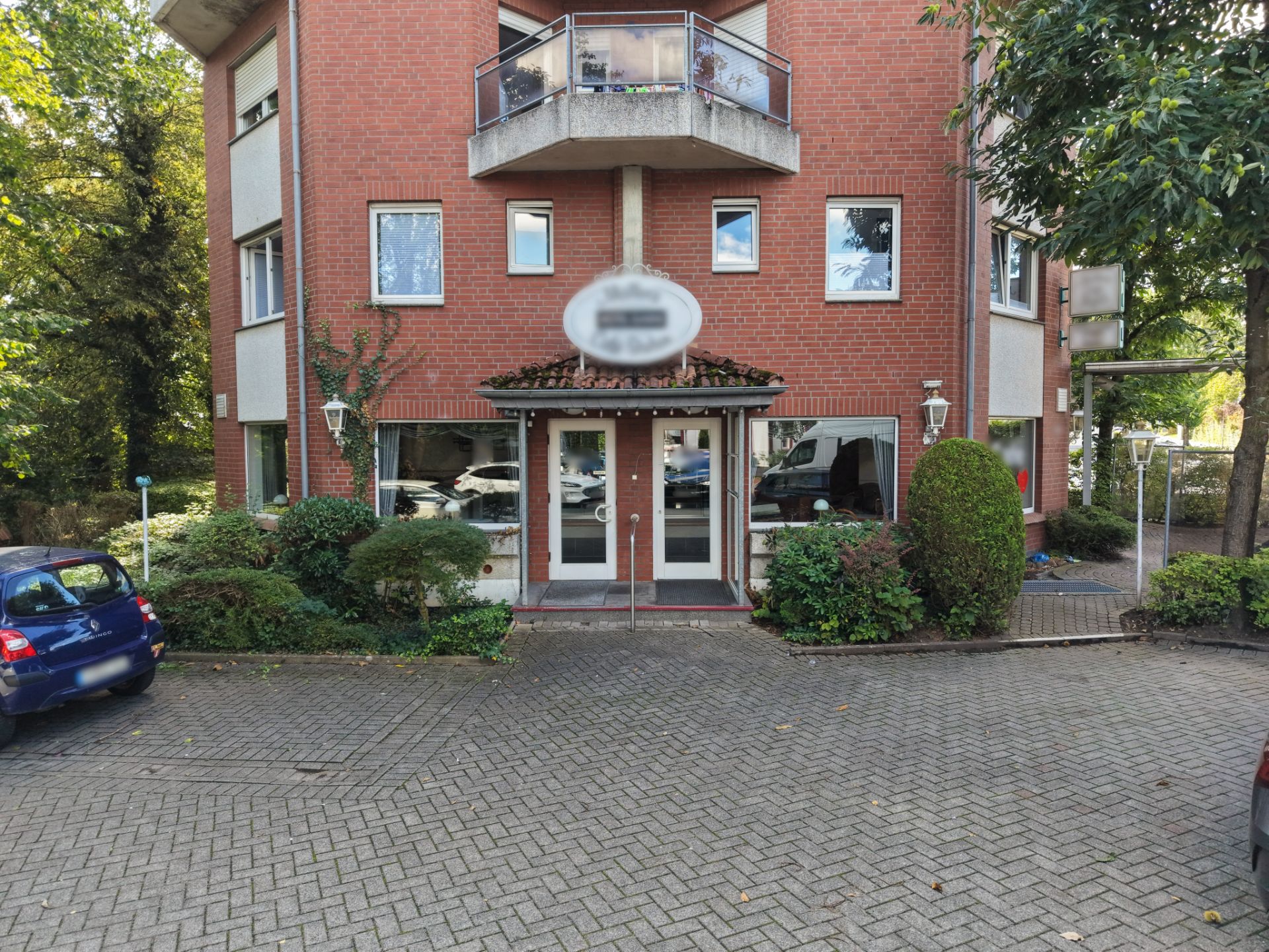 Eingang eines mehrstöckigen Wohnhauses mit roter Fassade und Balkon.