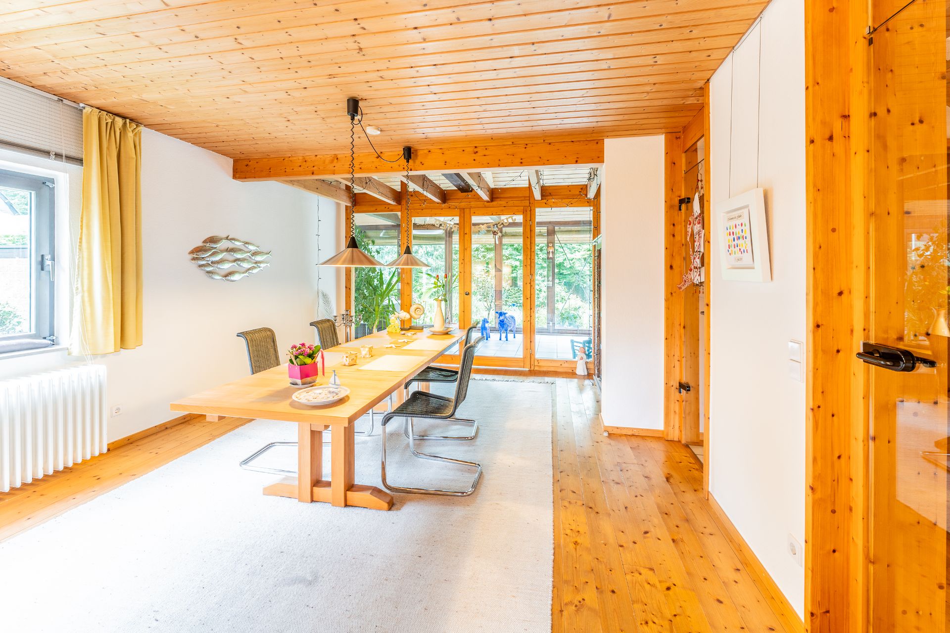 Heller Essbereich mit Holztisch, vier Stühlen und großen Fenstern zum Garten.