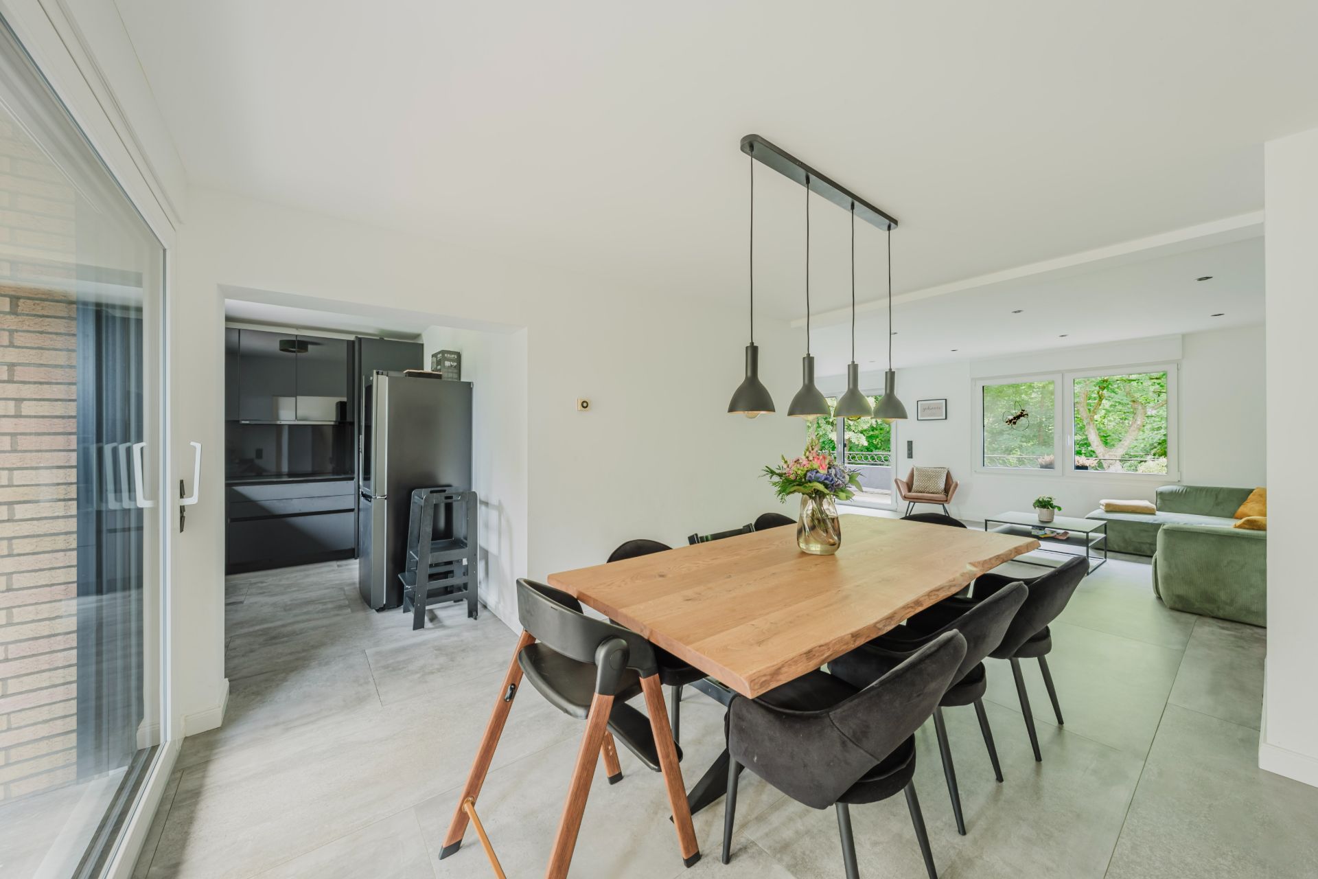 Helles Esszimmer mit Holztisch, schwarzen Stühlen und Blick ins Wohnzimmer und in die Küche.