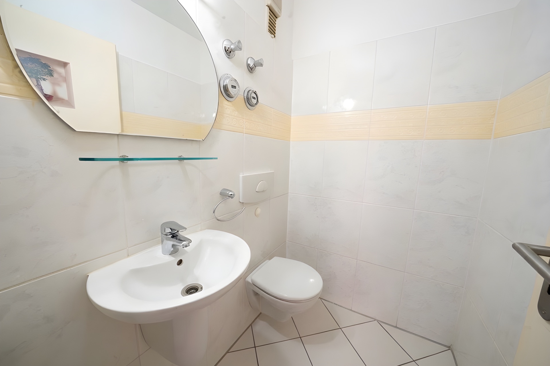 Kleines Badezimmer mit Waschbecken, Spiegel, Hängeregal und Wandtoilette.