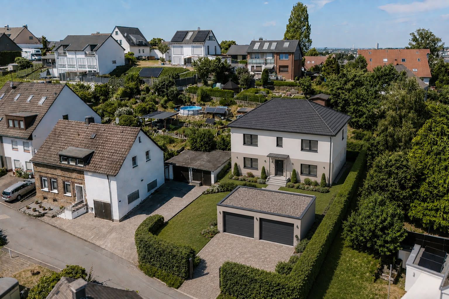 Luftaufnahme eines modernen Einfamilienhauses mit Doppelgarage und gepflegtem Garten.