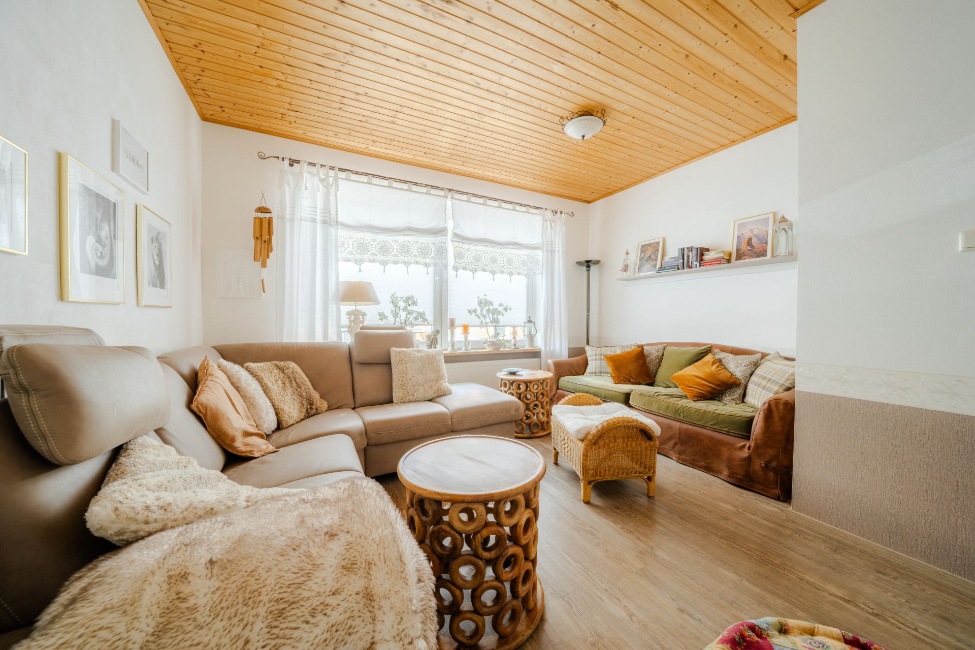 Helles Wohnzimmer mit Holzboden, Sofa, grünem Sofa, Couchtischen und großem Fenster.