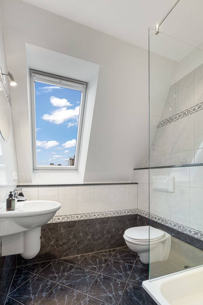 Modernes Badezimmer mit Fenster, Waschbecken, Toilette und Dusche.
