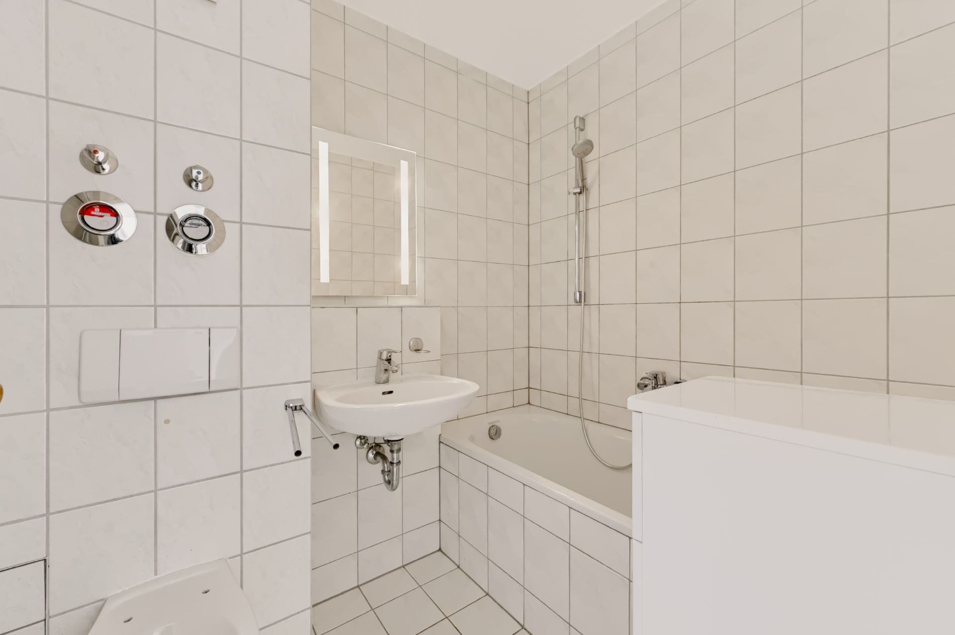 Helles Bad mit Badewanne, Waschbecken, Spiegel und weißen Fliesen.