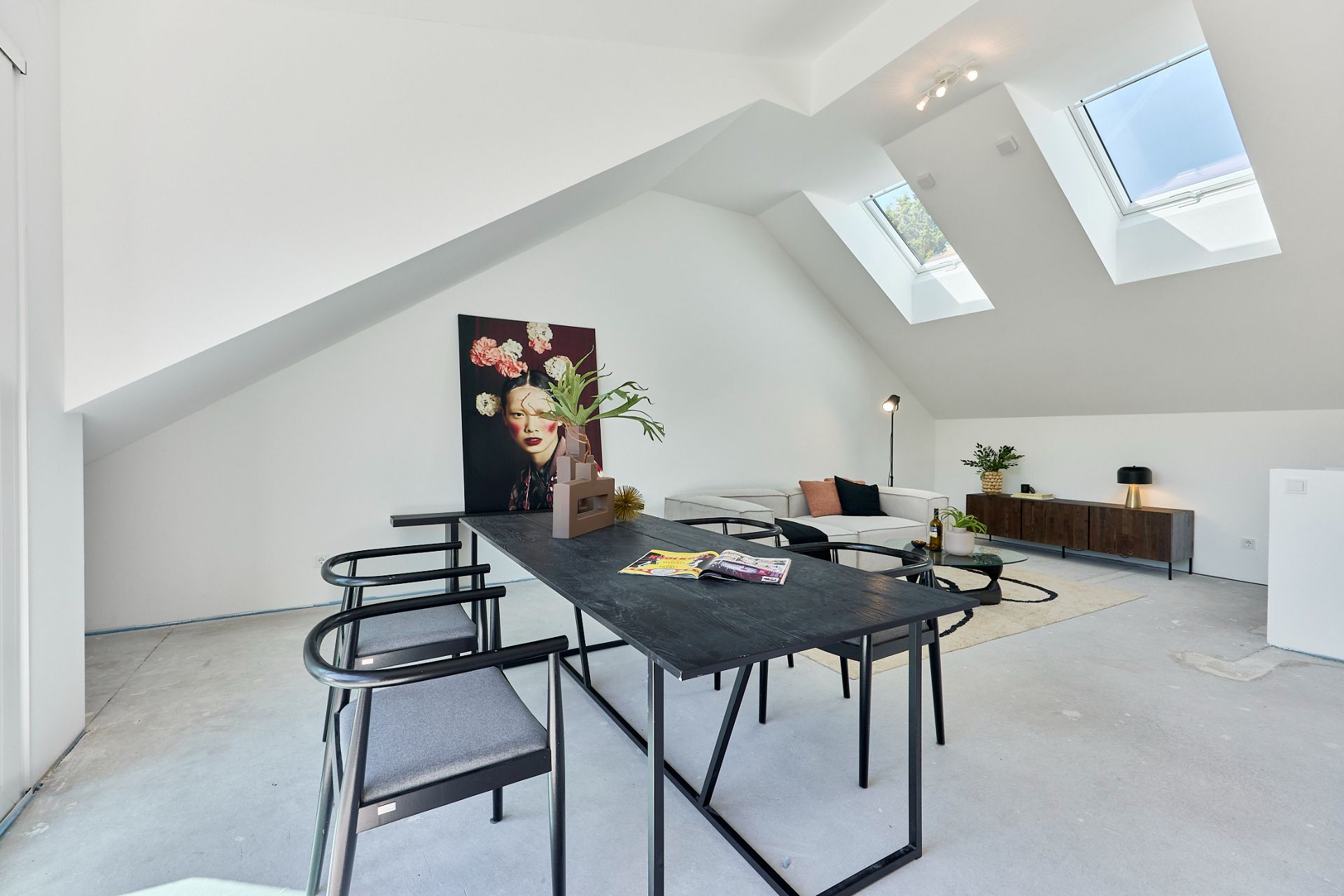Modernes Wohnzimmer mit schwarzem Tisch, Stühlen, Sofa und zwei Dachfenstern.