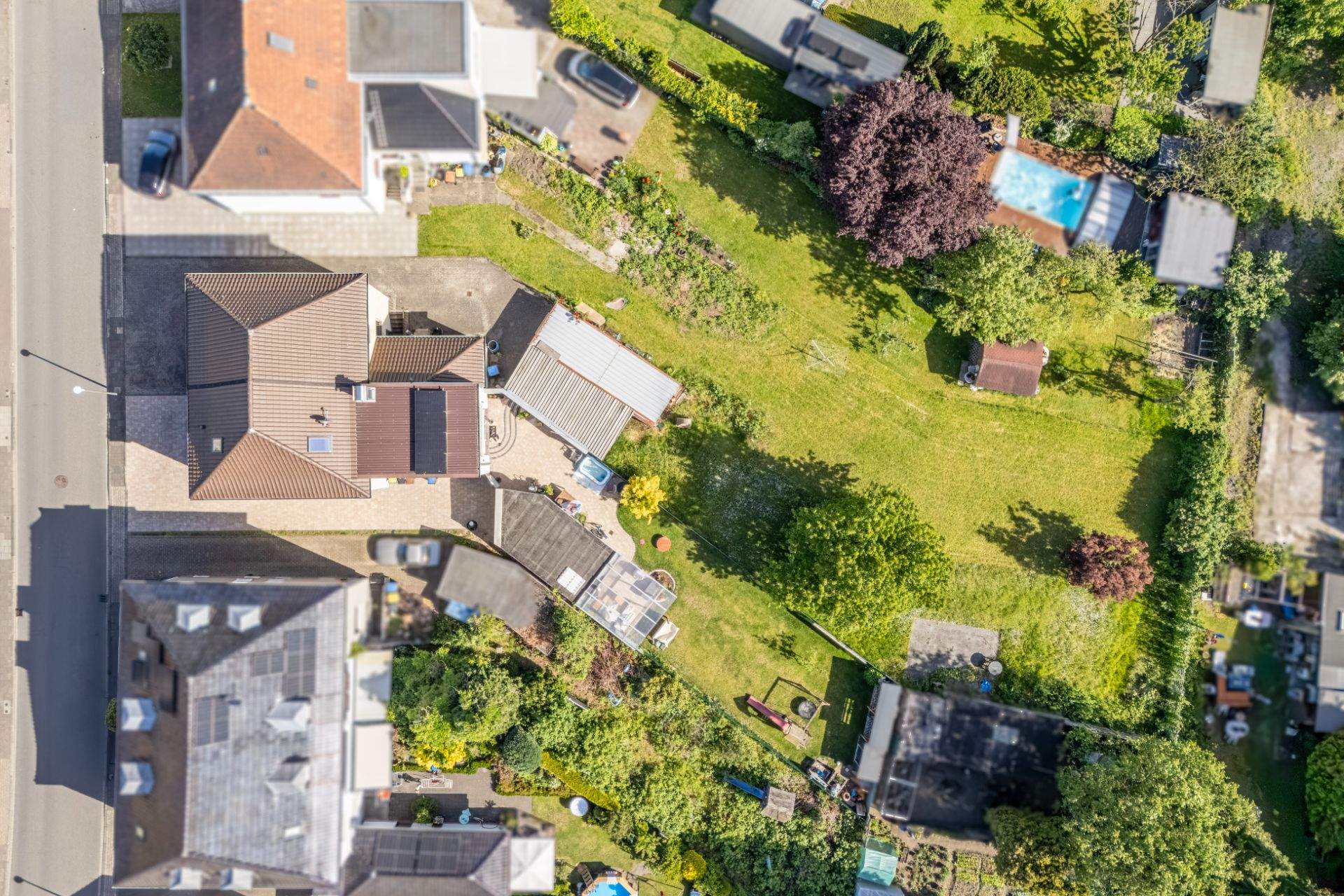 Luftaufnahme eines Wohnhauses mit großem Garten und umliegenden Häusern.