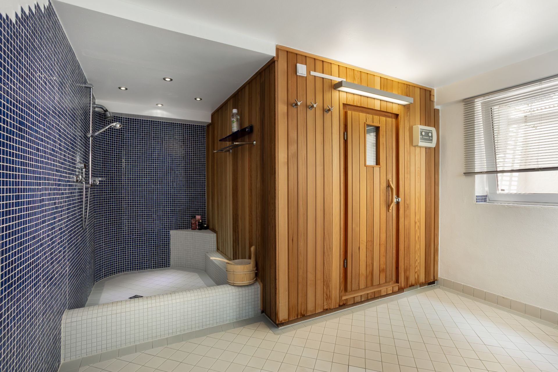Badezimmer mit Holzzauna und gefliestem Duschbereich auf der linken Seite.