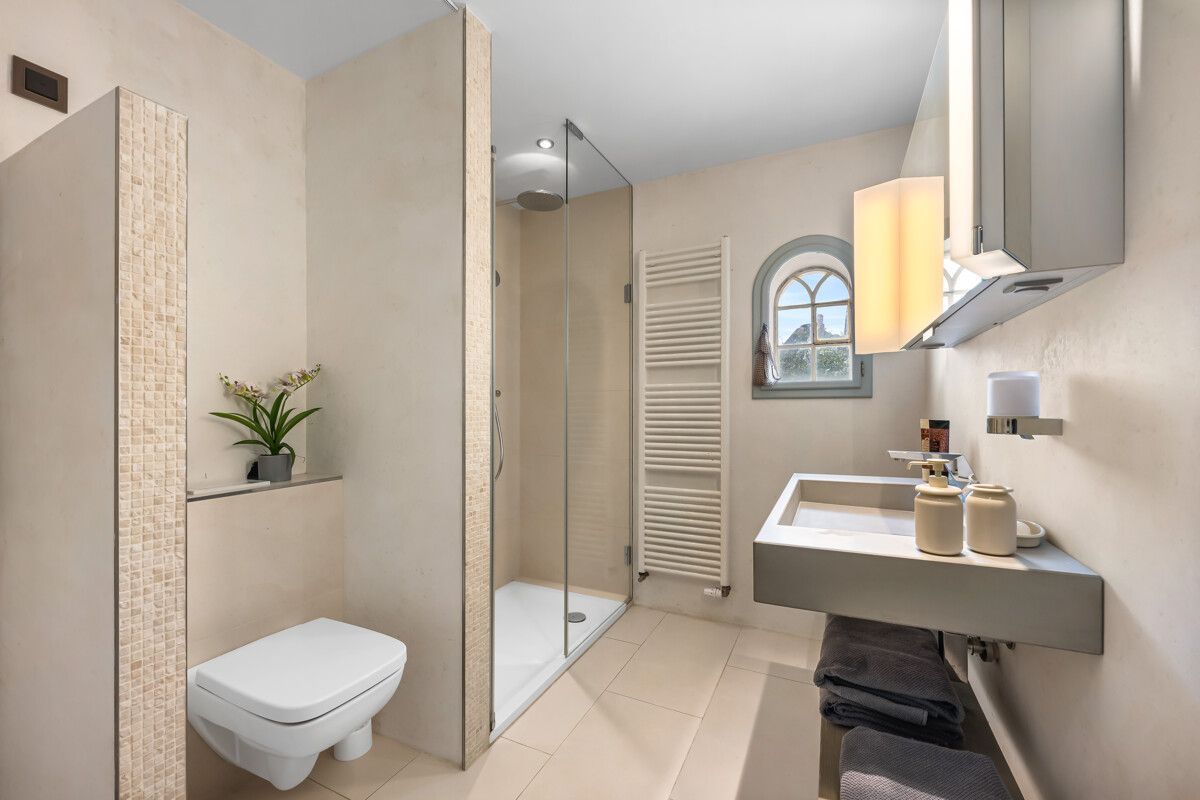 Modernes Badezimmer mit Dusche, Wand-WC, Waschbecken und kleinem Fenster.