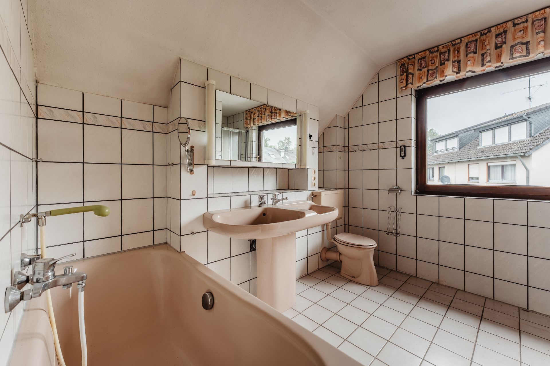 Badezimmer mit Badewanne, Waschbecken, Toilette und großem Fenster, alles in beigem Stil.