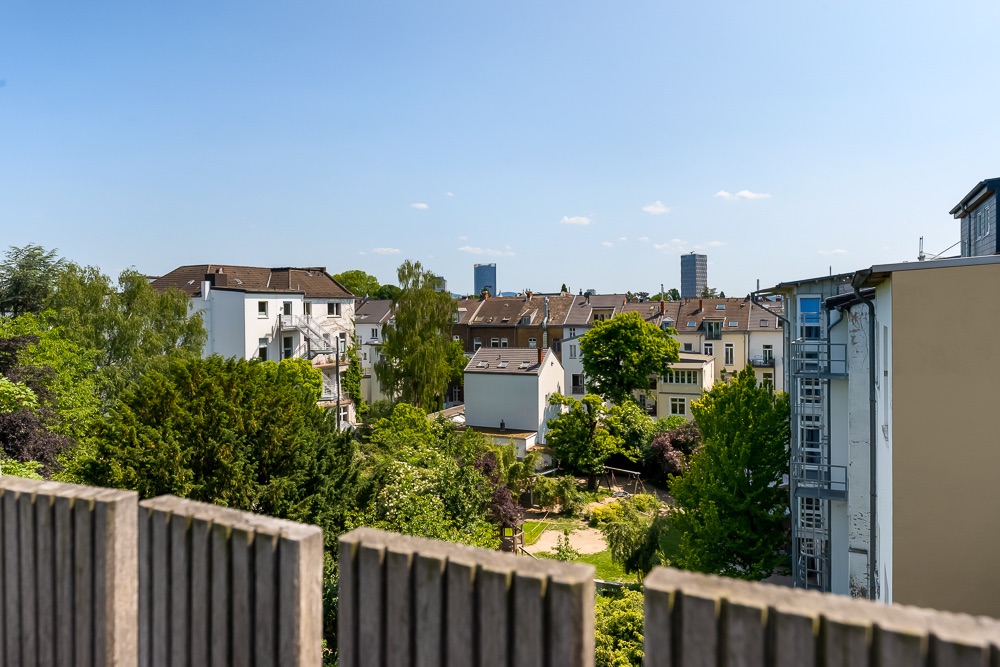 Blick über grüne Innenhöfe und Wohnhäuser an einem sonnigen Tag.