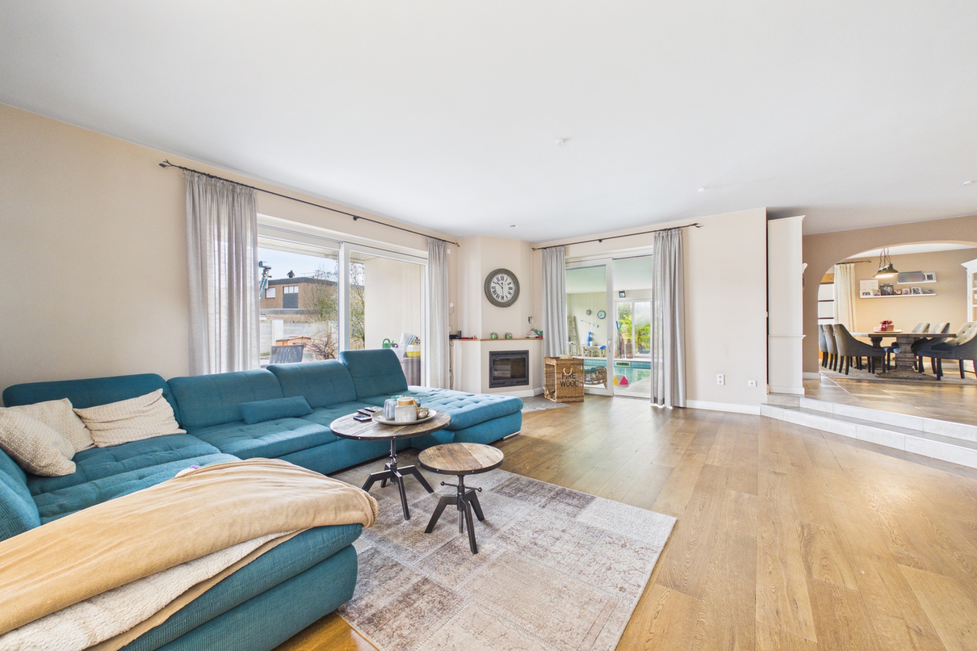 Helles Wohnzimmer mit blauem Sofa, Couchtischen und großem Fenster zur Terrasse.