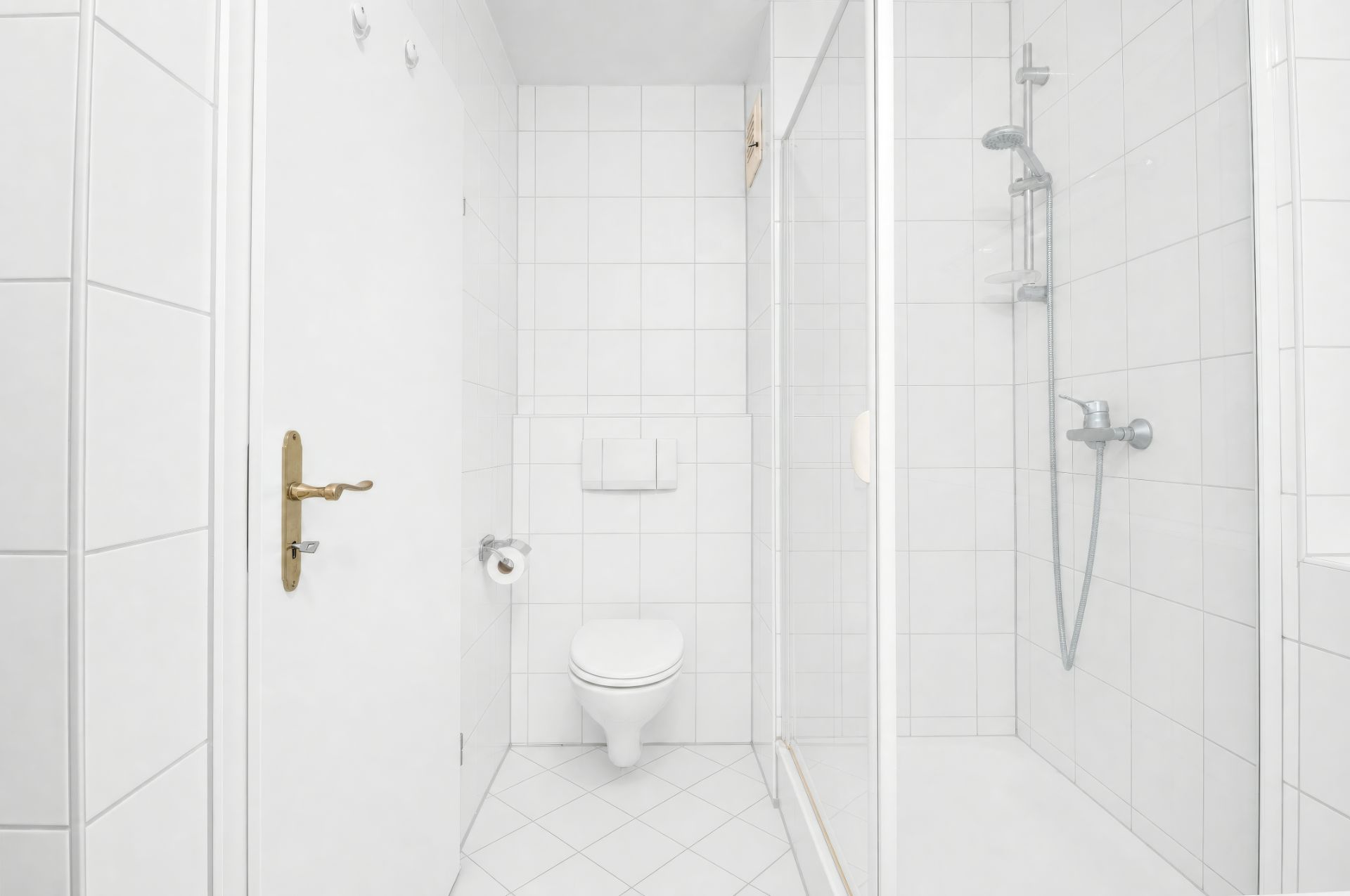 Helles Badezimmer mit weißem WC, Toilettenpapier und Dusche mit Glastür.