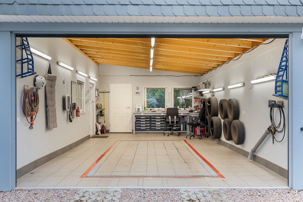 Garage mit Werkbank, Reifen an der Wand und Werkzeugen, gut beleuchtet mit Fliesenboden.