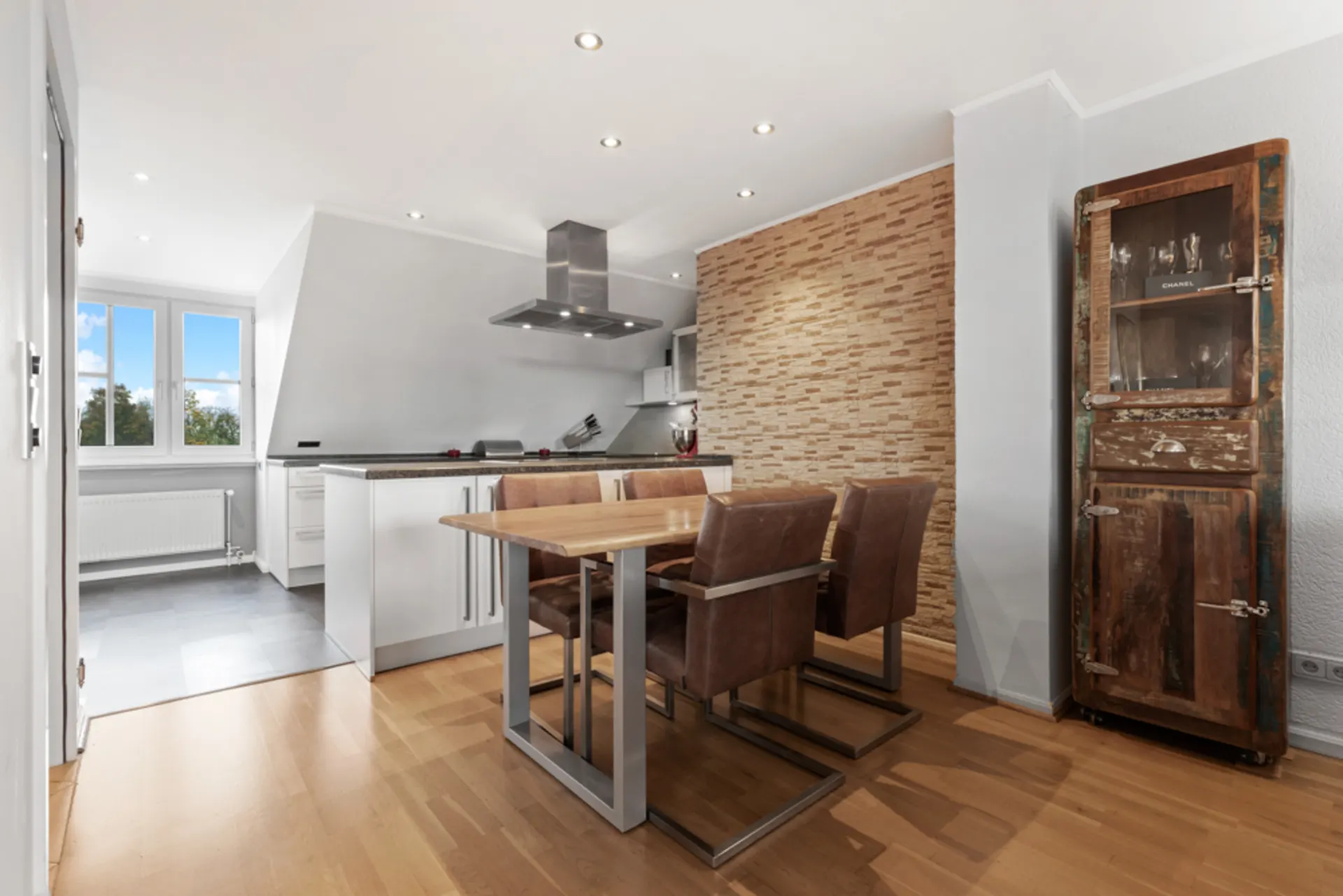 Moderne Wohnküche mit Esstisch, vier Stühlen und rustikalem Holzschrank.