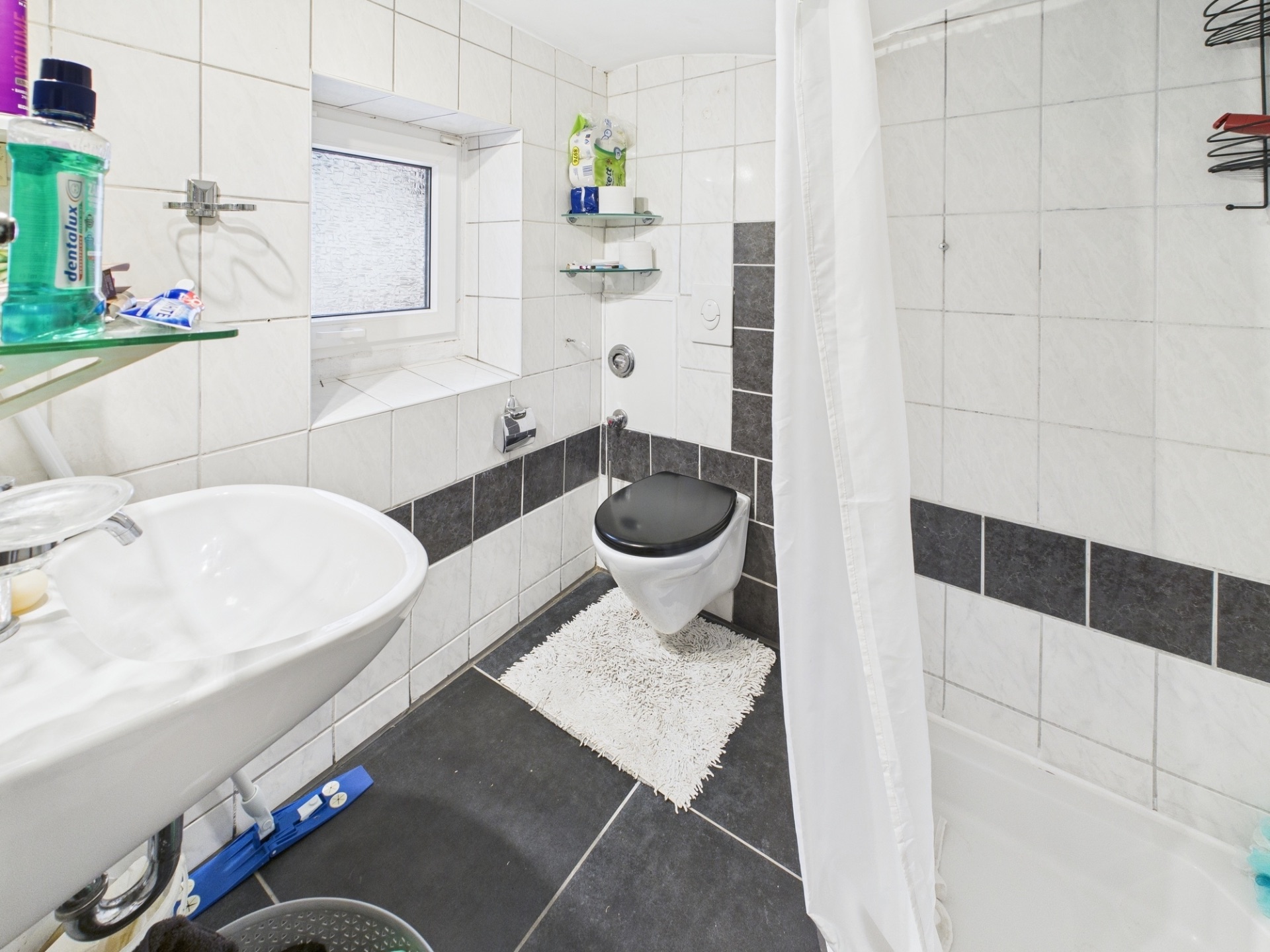 Modernes Badezimmer mit Waschbecken, Wandtoilette, Dusche und kleinem Fenster.