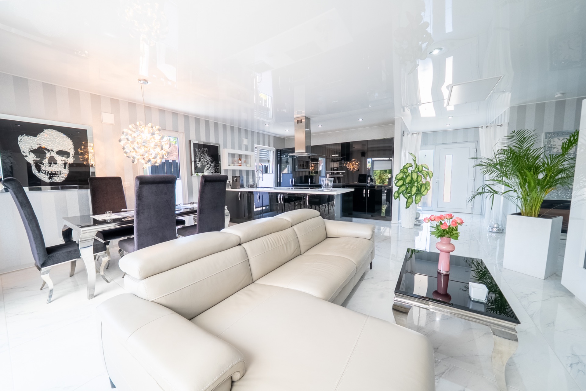 Modernes Wohnzimmer mit beiger Couch, Essbereich, Pflanzen und großem Spiegel an der Wand.