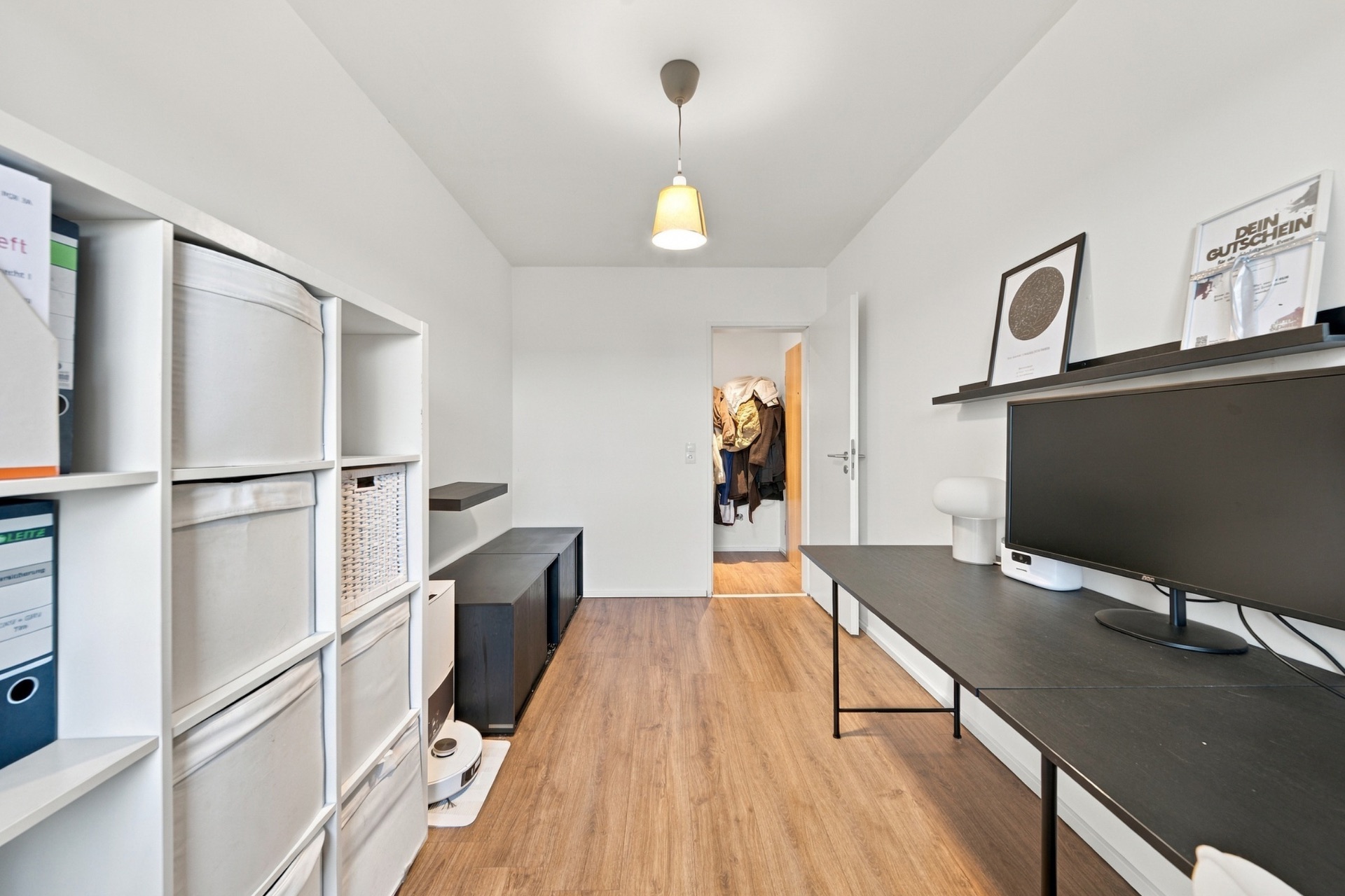Modernes Arbeitszimmer mit Schreibtisch, Regal, Computer und Holzfußboden.