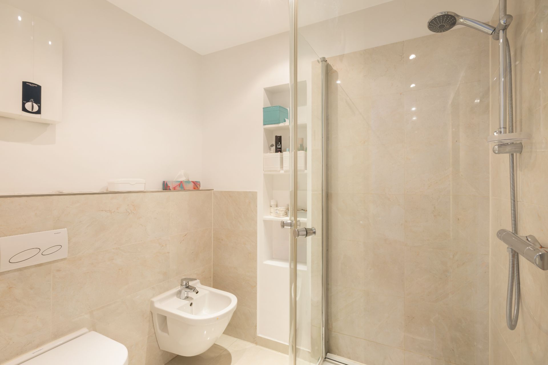Modernes Badezimmer mit Dusche, Bidet und WC, hell gefliest.