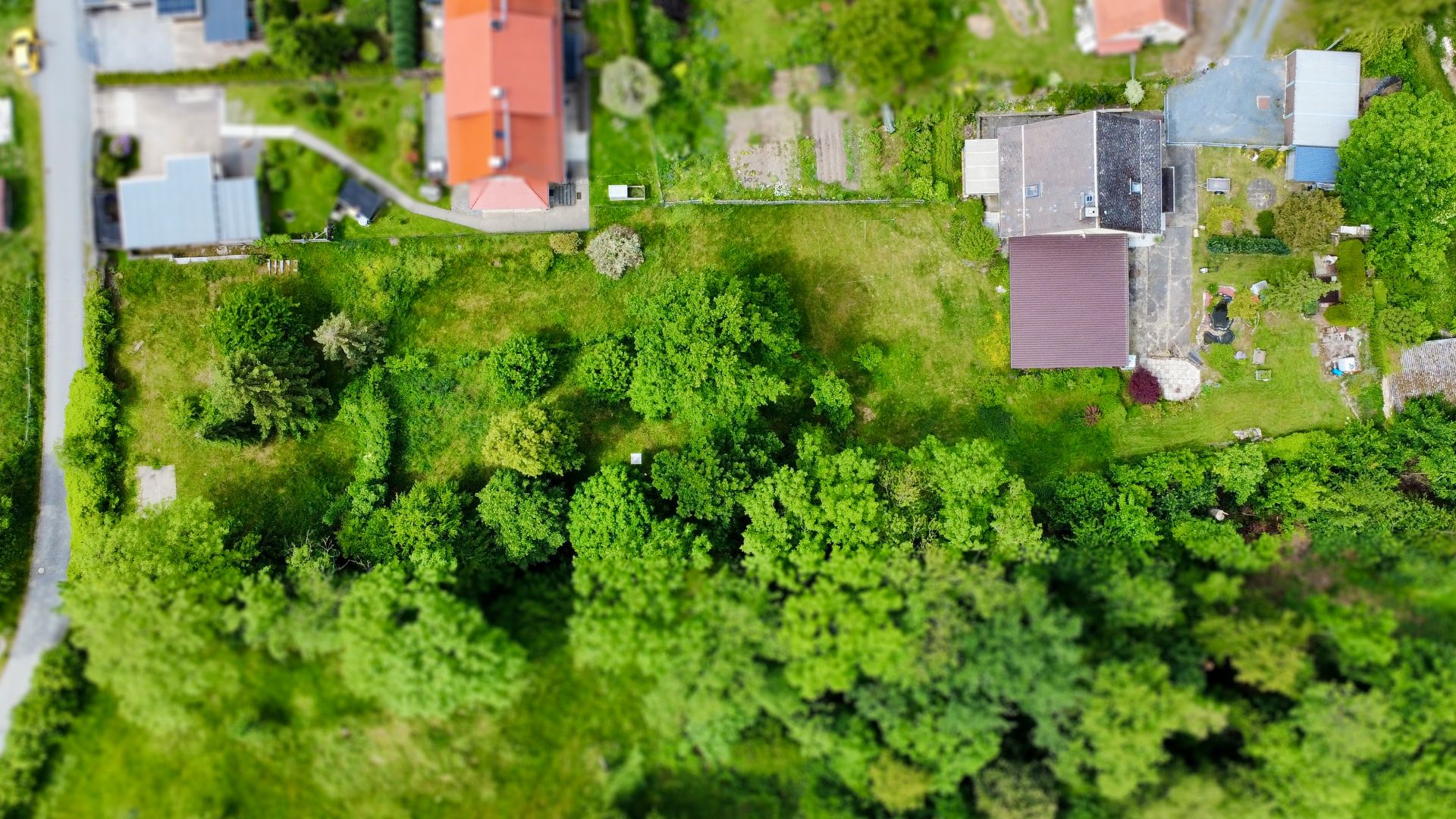 Luftaufnahme eines Hauses mit großem Garten und umliegenden Bäumen.