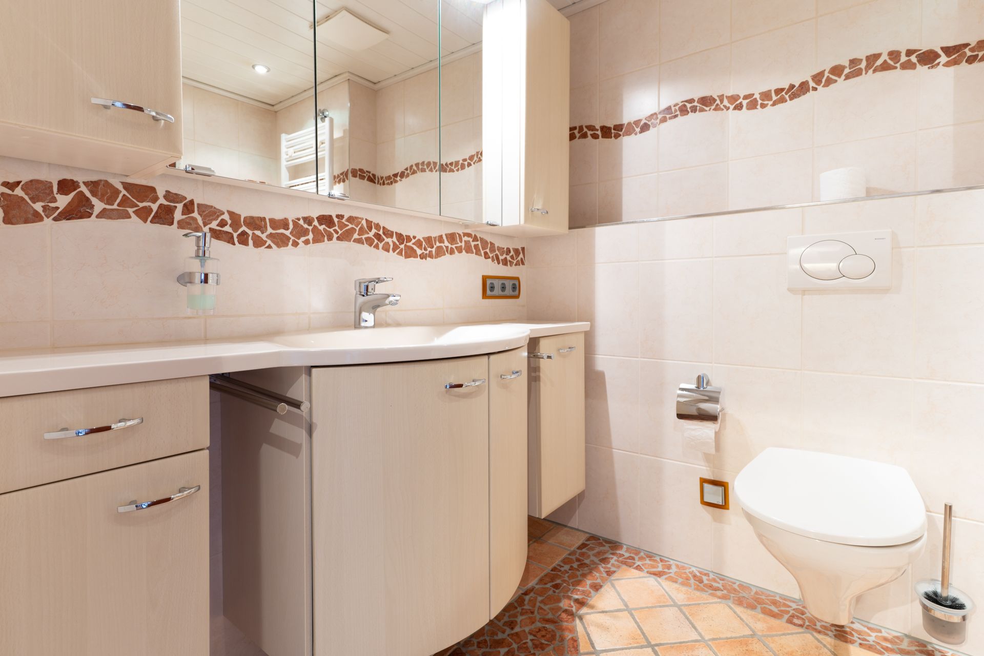 Modernes Badezimmer mit hellen Schränken, Spiegeln, Waschbecken und wandhängender Toilette.