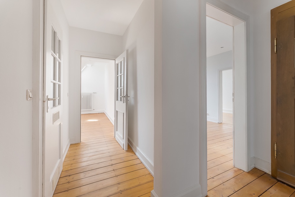 Heller Flur mit Holzboden und weißen Türen, mehrere angrenzende Zimmer sichtbar.