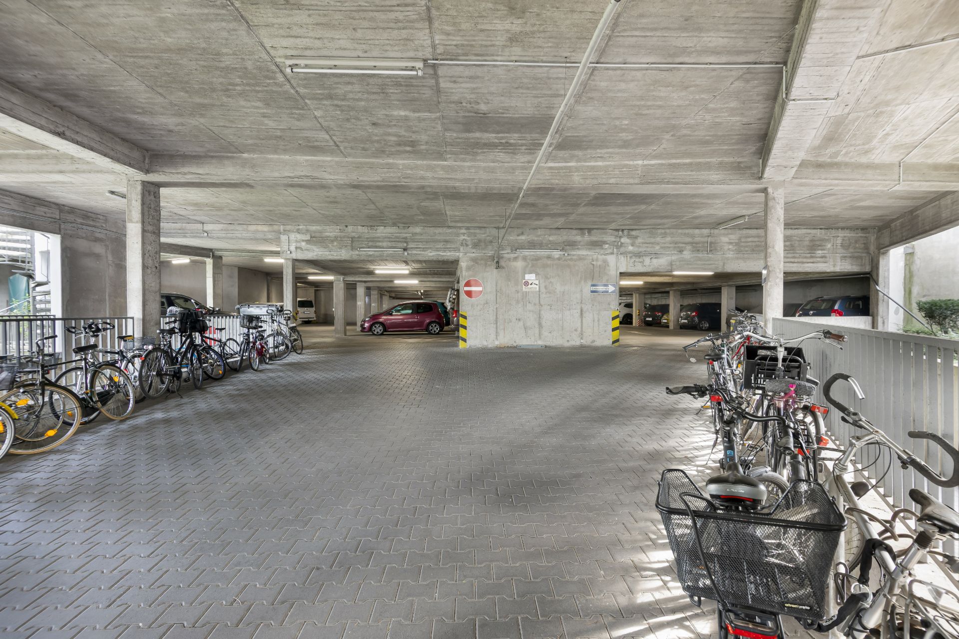 Tiefgarage mit geparkten Autos und Fahrrädern in einem Wohngebäude.