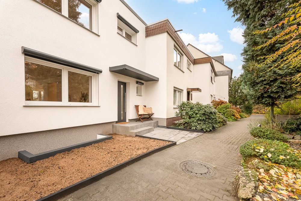 Außenansicht eines modernen Wohnhauses mit Vorgarten und gepflastertem Weg.