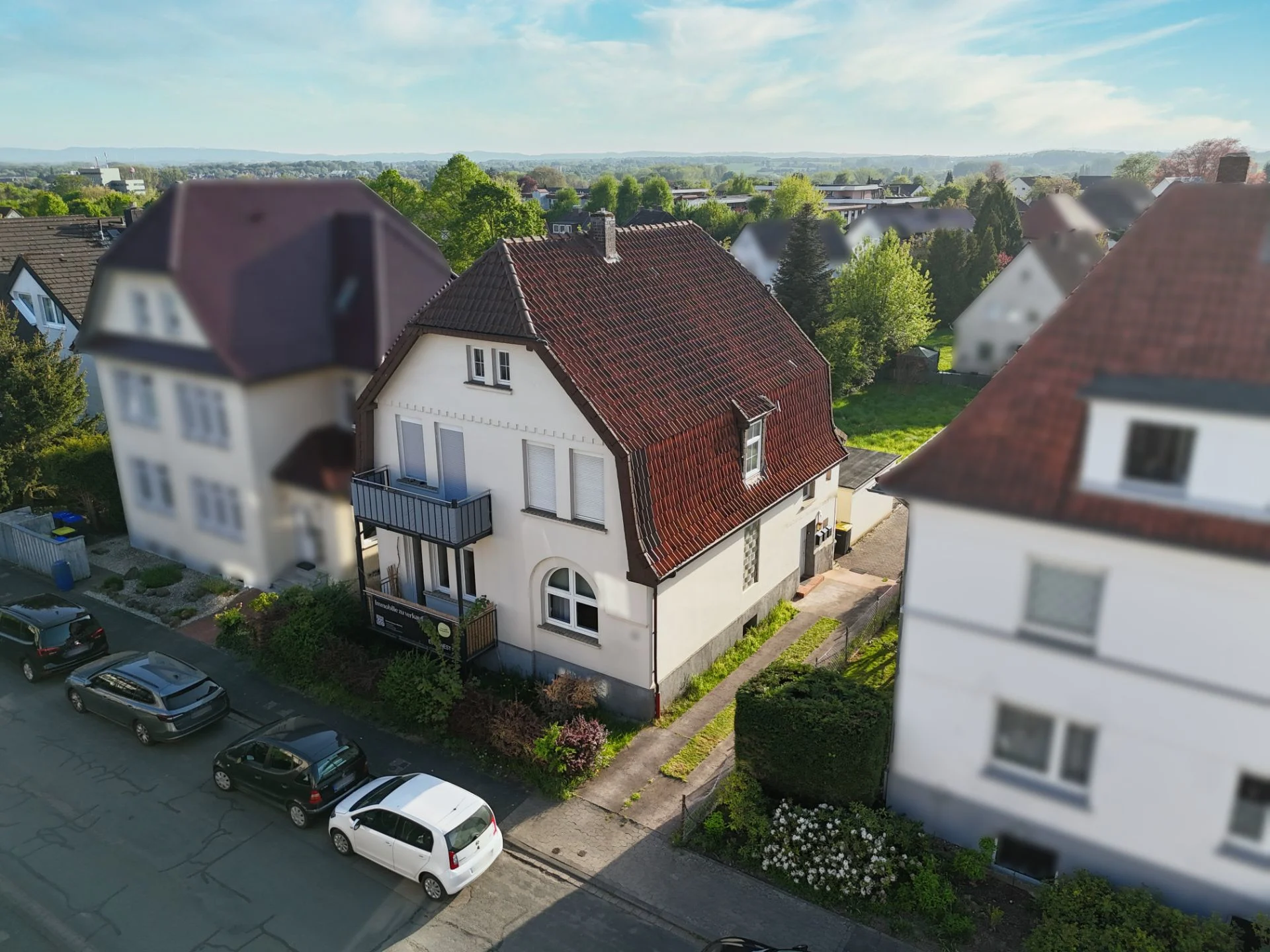 Zweistöckiges Wohnhaus mit rotem Dach und Vorgarten in einer Vorstadtsiedlung.