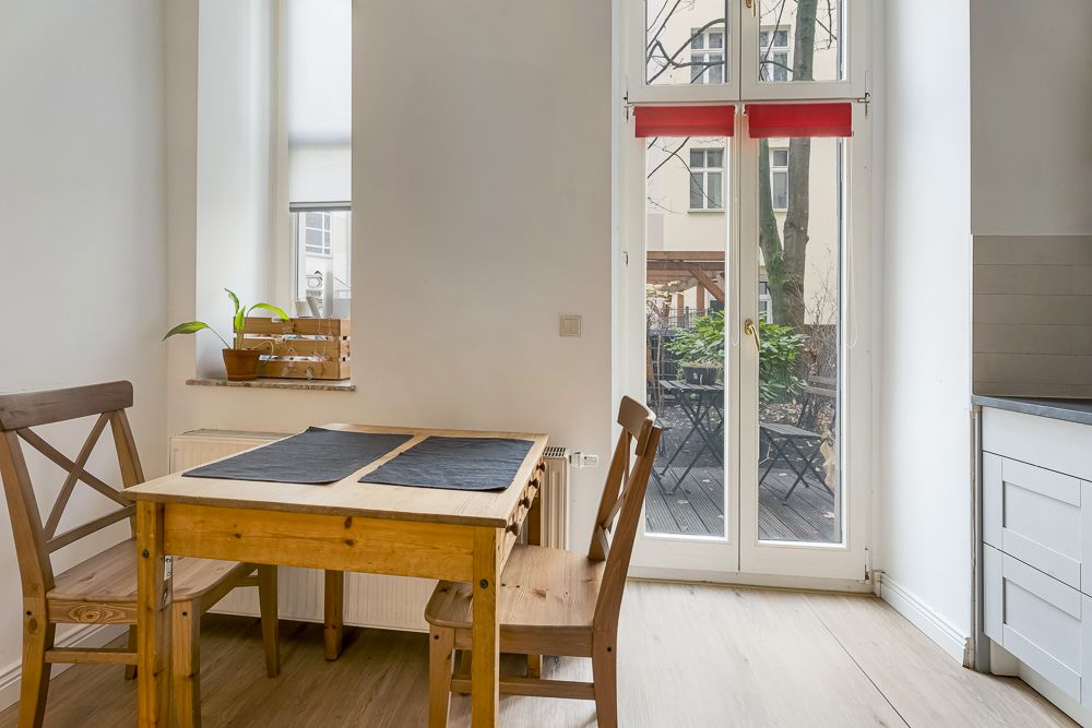 Heller Essbereich mit Holztisch, drei Stühlen und Zugang zur Terrasse durch Glastüren.