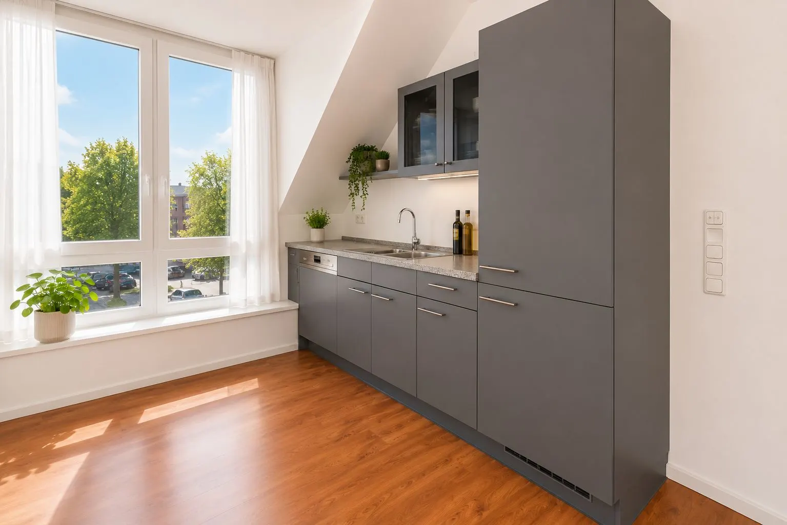 Moderne Küche mit grauen Schränken, großem Fenster und Holzboden.