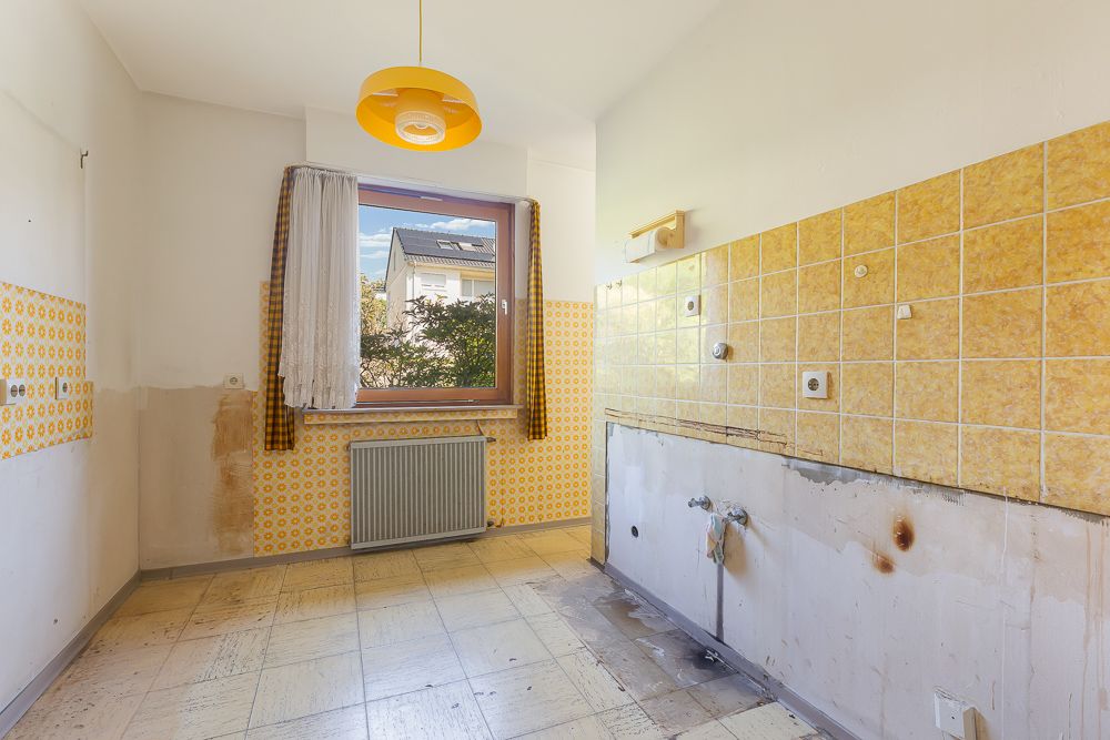 Leerer Raum mit gelben Wandfliesen, Fenster mit Vorhang und Radiator darunter.