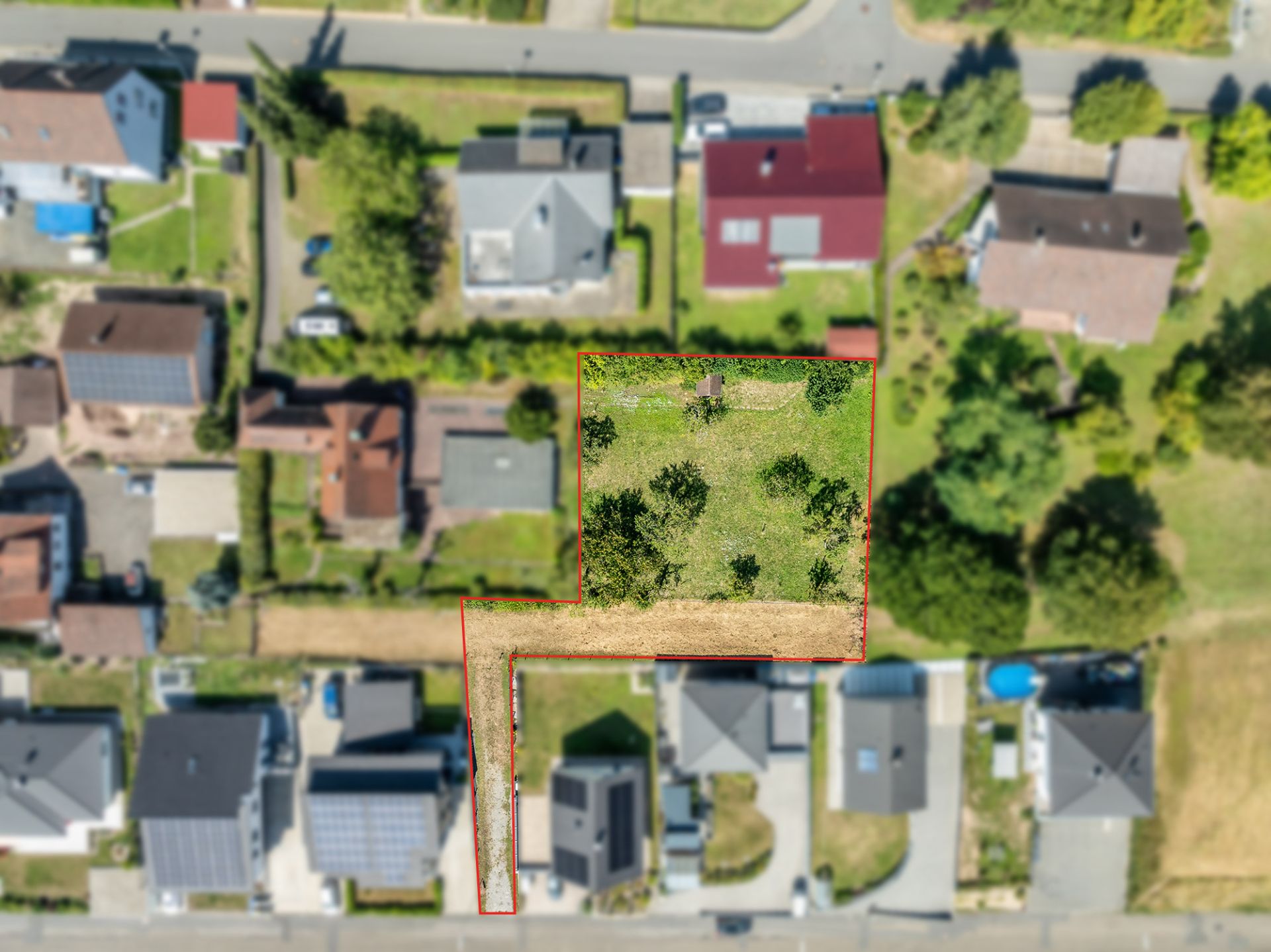 Luftaufnahme eines Wohngebiets mit markiertem Gartengrundstück und Bäumen.