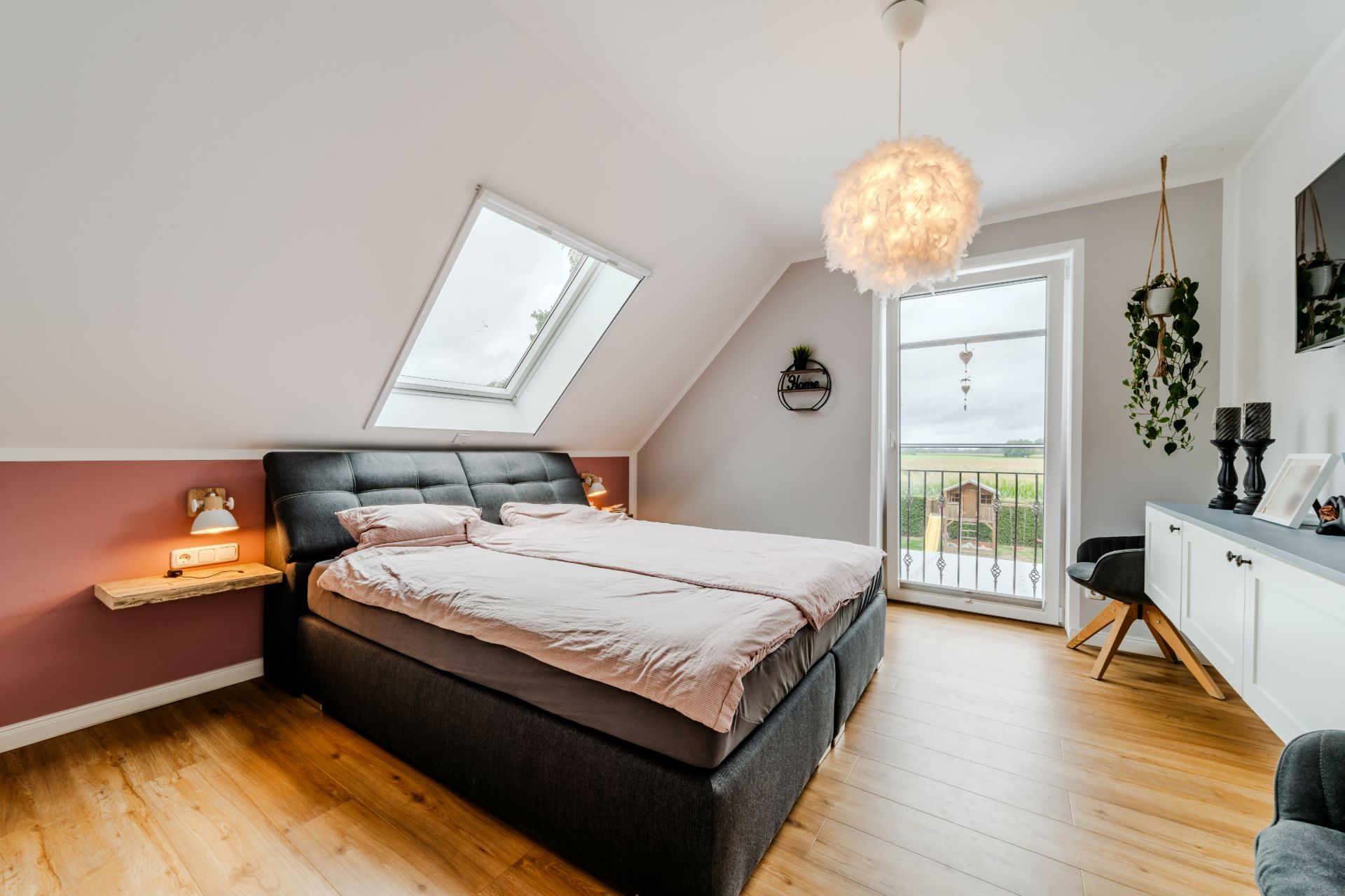 Modernes Schlafzimmer mit Doppelbett, Dachfenster und Balkonzugang, Holzboden und dekorativen Elementen.