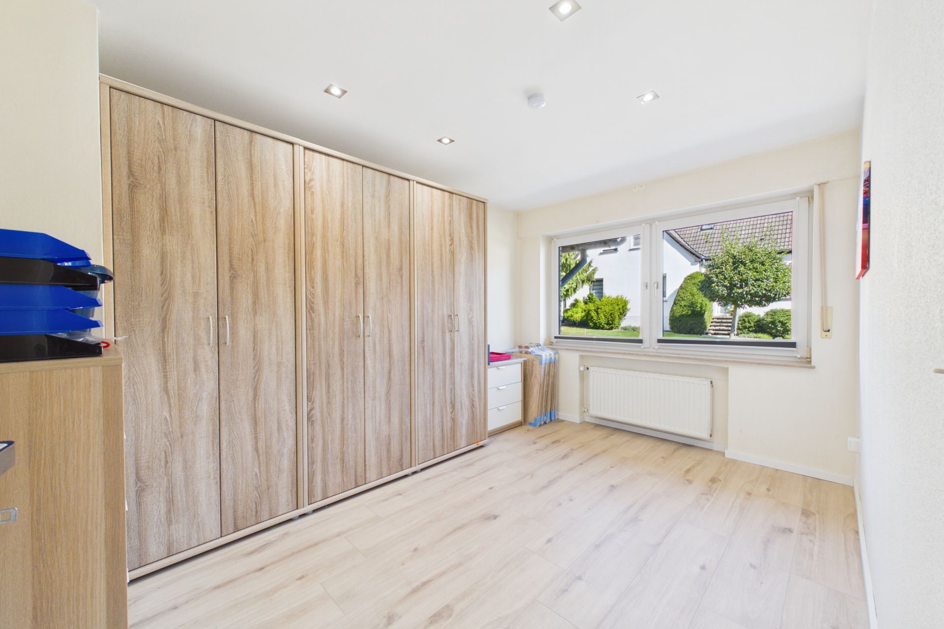 Helles Zimmer mit großem Holzkleiderschrank, Fenster und Blick auf den Garten.