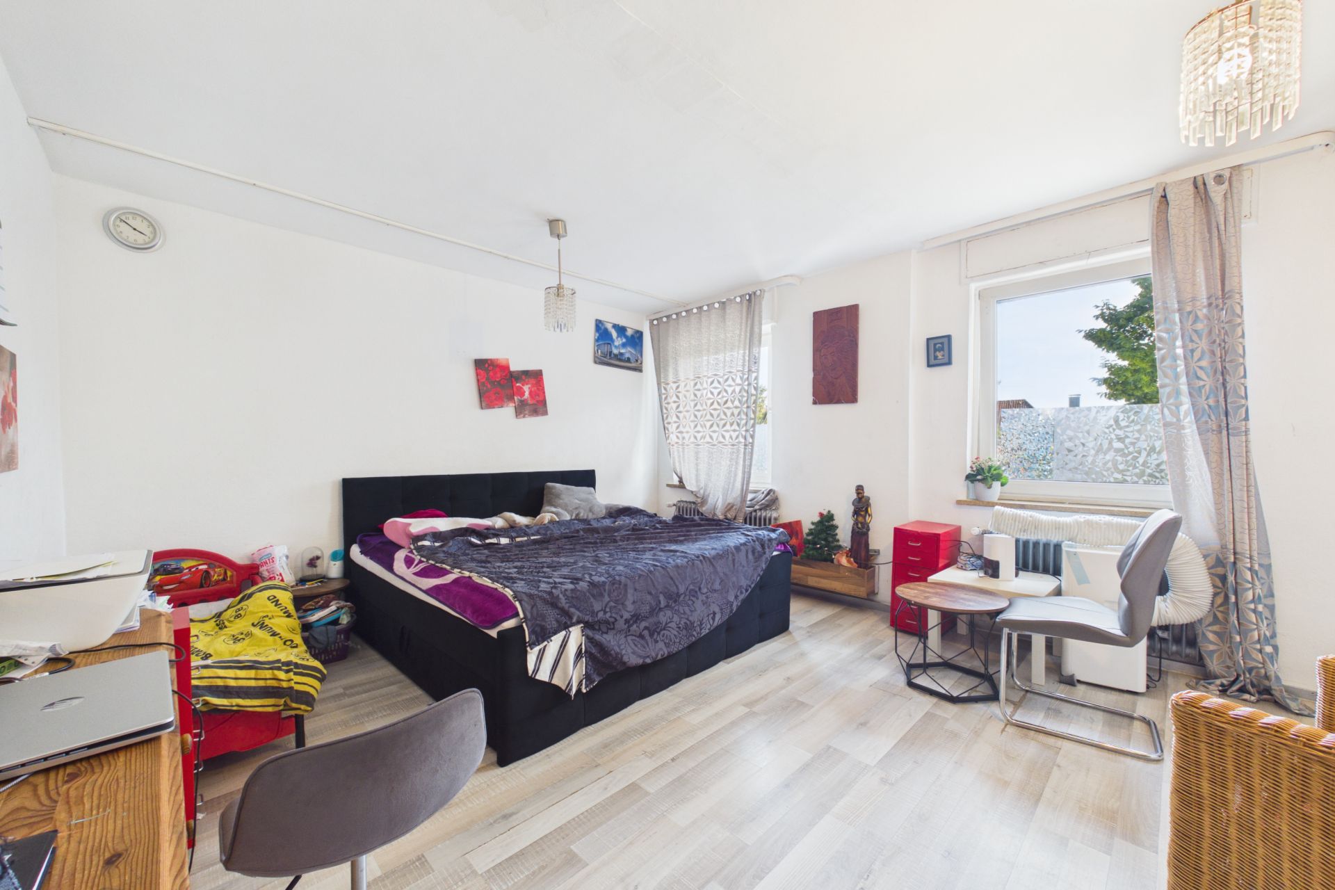 Helles Schlafzimmer mit Doppelbett, Schreibtisch, Stühlen und großem Fenster.